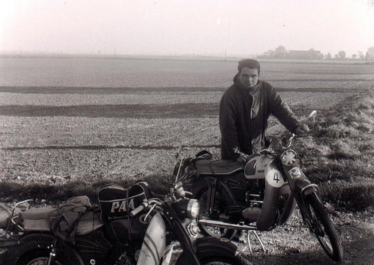 A young Ralf G. Bahr standing beside a motorcycle with a PAA-stenciled side bag in a German farm field, late 1960s.