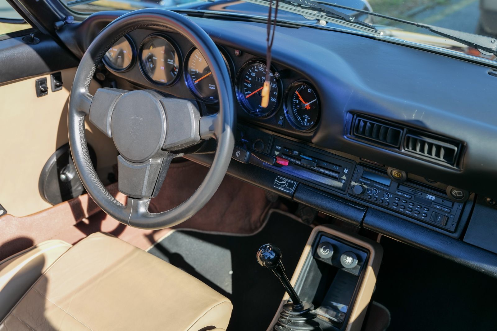 Classic Porsche 911 dashboard with five gauges, central tachometer and tan leather interior