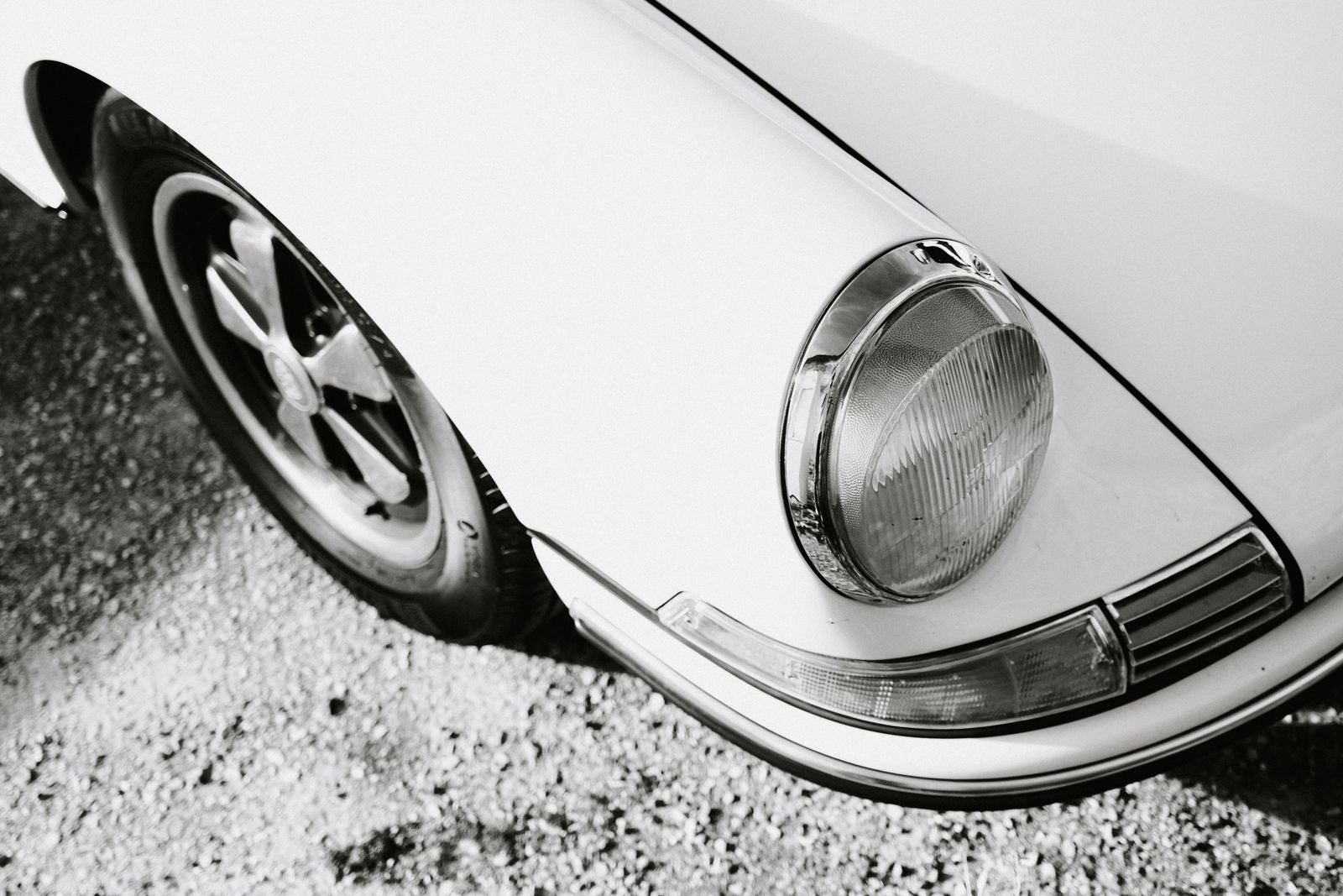 Classic Porsche 911 headlight and Fuchs wheel in monochrome.