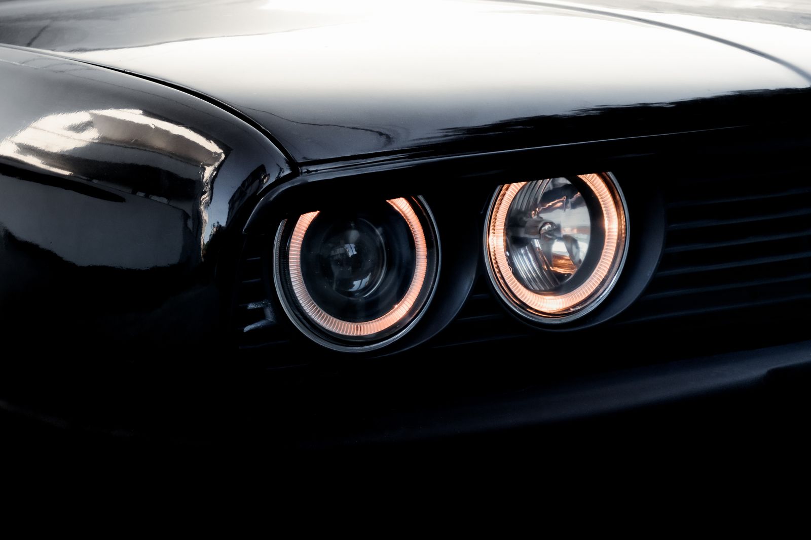 Halo headlights of a classic coupe on black.