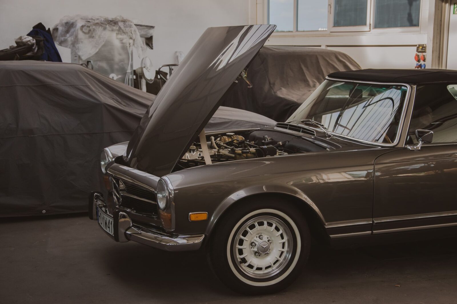 Classic Mercedes SL with its hood open in a specialist workshop.