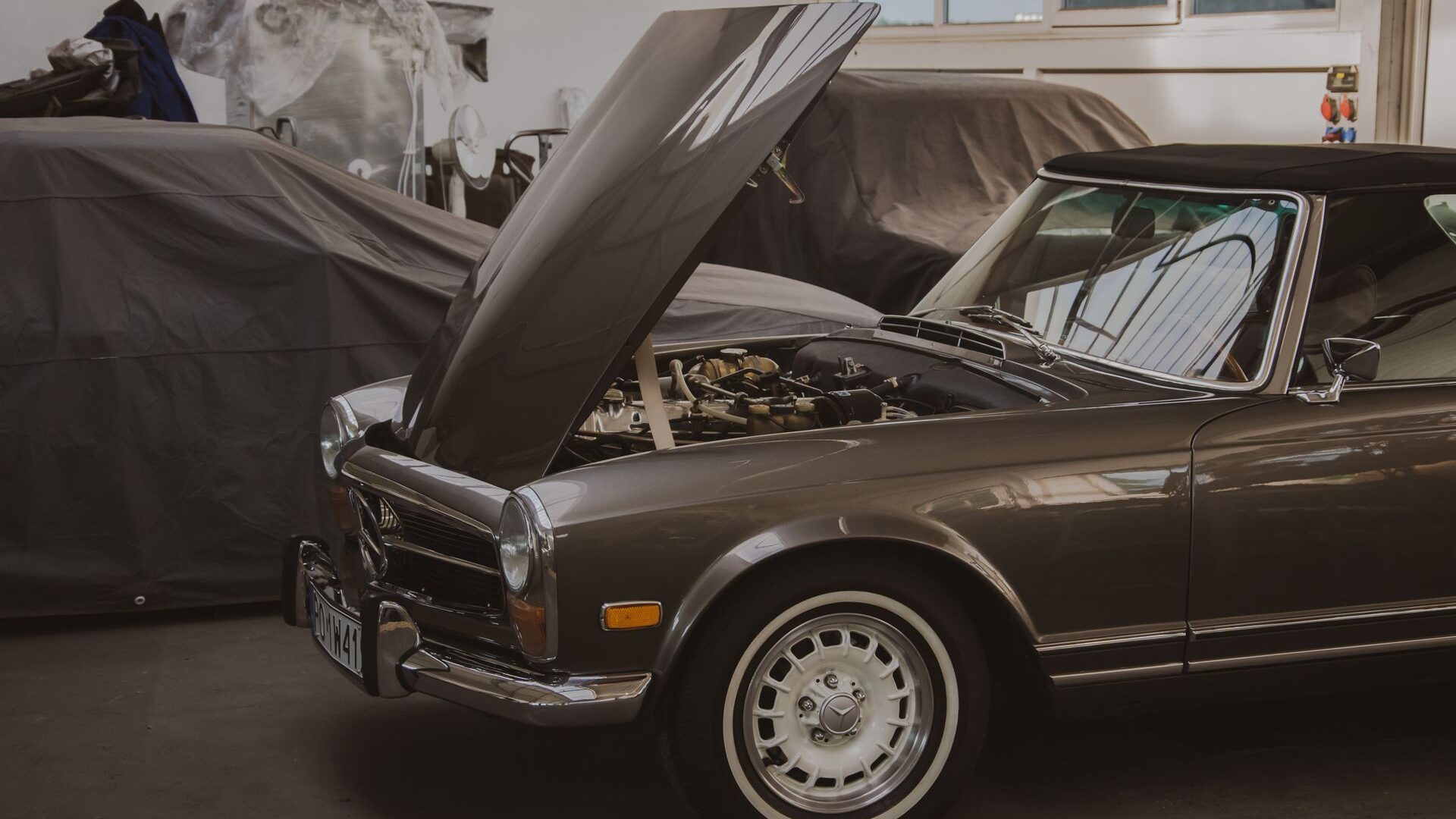 Classic Mercedes SL with its hood open in a specialist workshop.